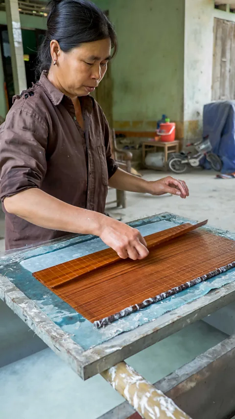 A woman arranging the woven bamboo screen used to pull Dó paper
